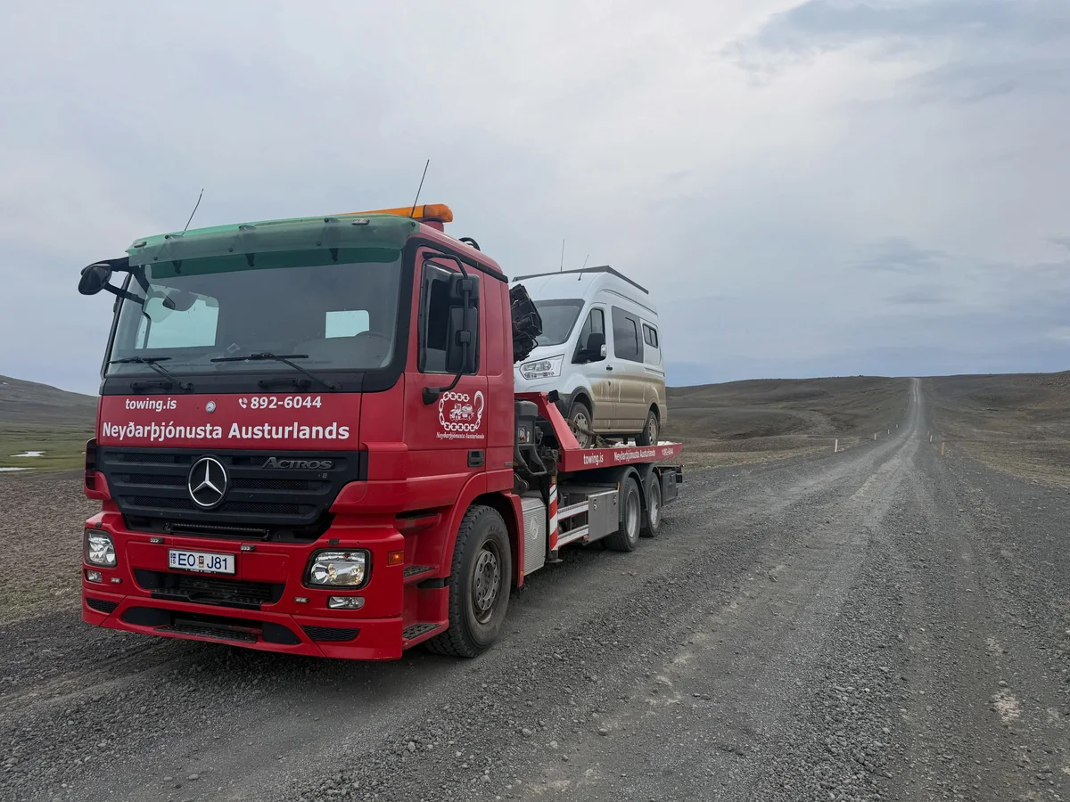 Red Towing.is recovery truck transporting a campervan on a gravel road