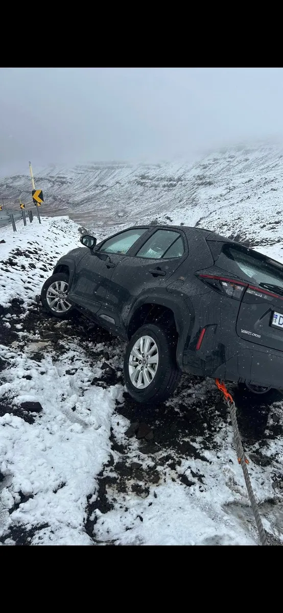 Toyota Yaris Cross in a snowy roadside ditch with a recovery strap attached